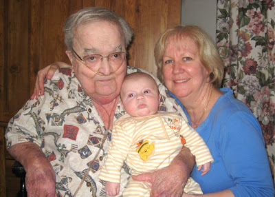A grandpa and grandma holding their infant grandson