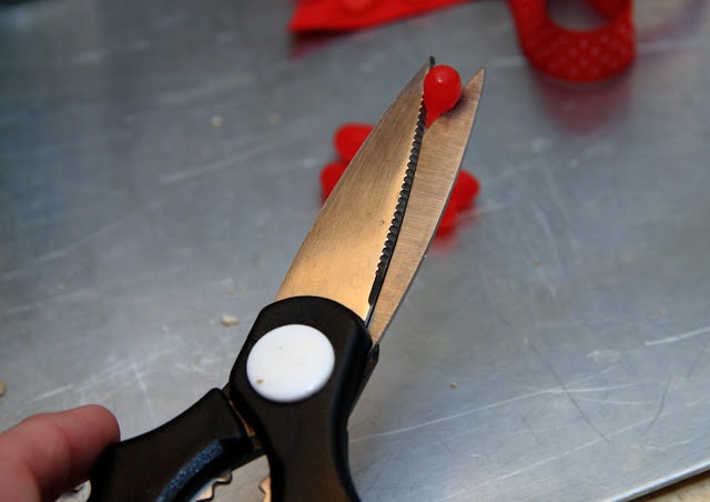 scissors cutting red candies in half