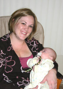 a mom sitting in a chair, holding a baby in a yello jumper
