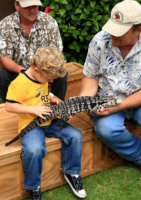 A group of people holding a big lizard