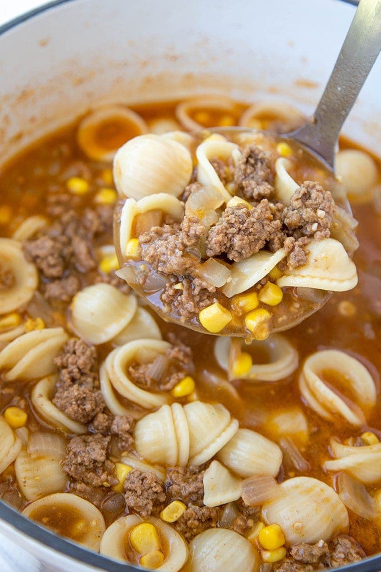 hamburger soup on a ladle with pasta and corn