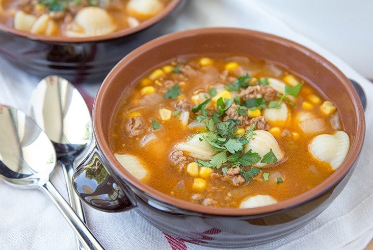 This Hamburger Soup Recipe is hearty and delicious, easily customizable and ready in less than 30 minutes, making it a delicious and quick dinner option. soup with pasta and hamburger in a brown bowl.