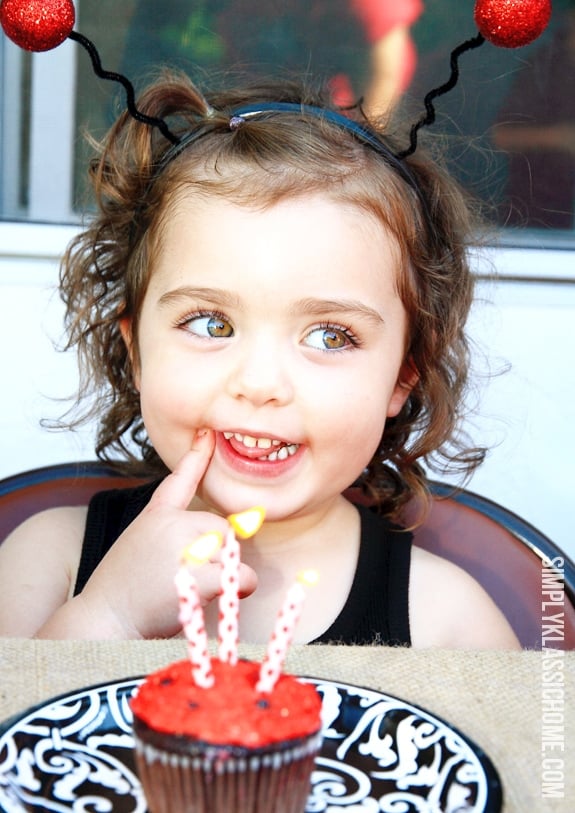 A young girl and a birthday cupcake with candles