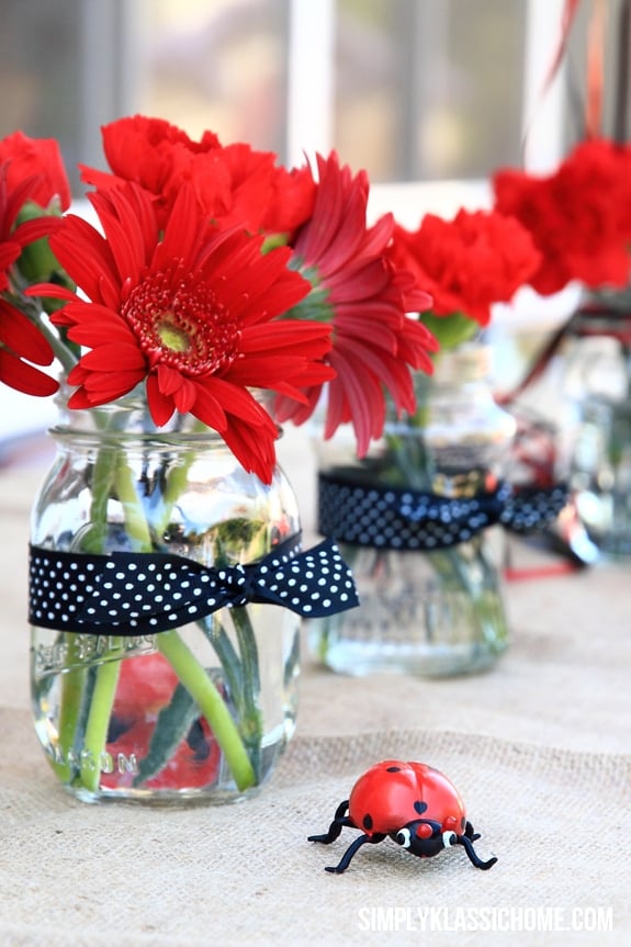 Clear vases of red flowers on a table