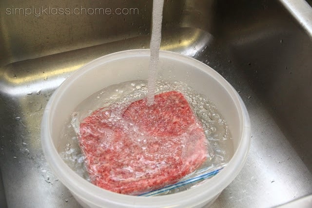 A bowl of water with plastic wrapped ground beef