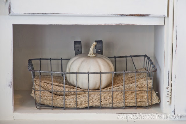 A close up of a white pumpkin in wire basket