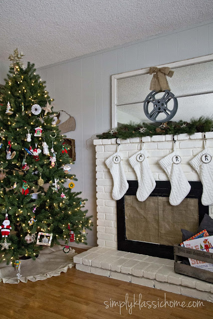 A living room with a Christmas tree and fireplace with stockings