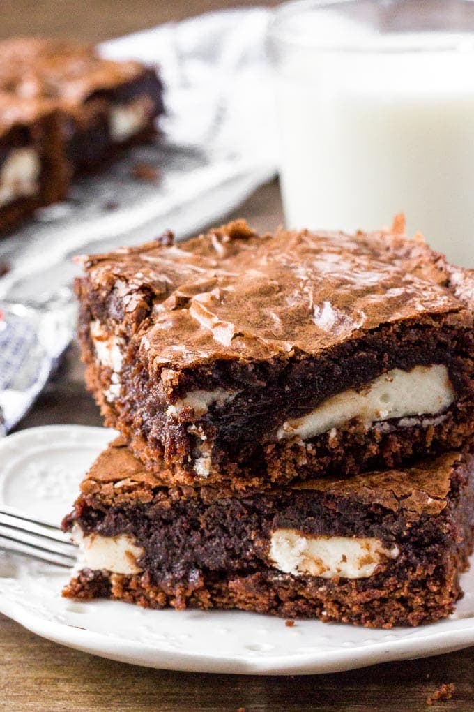 Two Peppermint Patty Brownies on a plate served with a glass of milk.