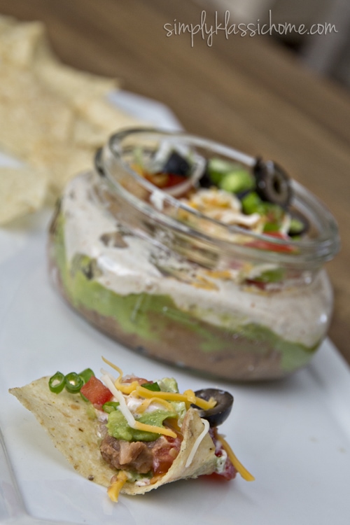 A bowl of dip with chips on a plate