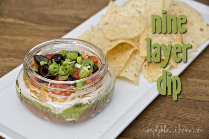 A jar of nine layer dip on a plate with chips