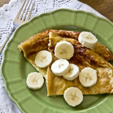 A green plate with pancakes and bananas