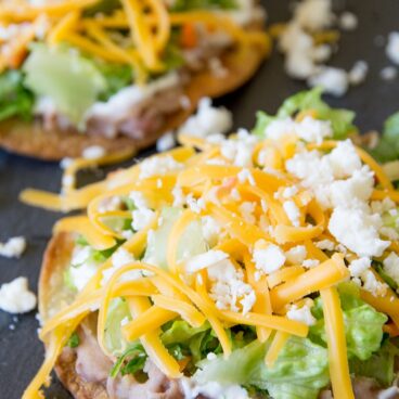 Baked tostadas with beans, lettuce and cheese social media image.