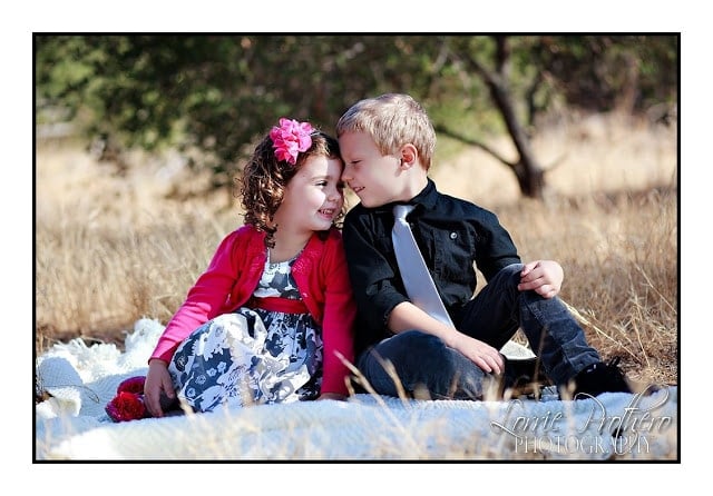 A little girl and boy sitting in the grass