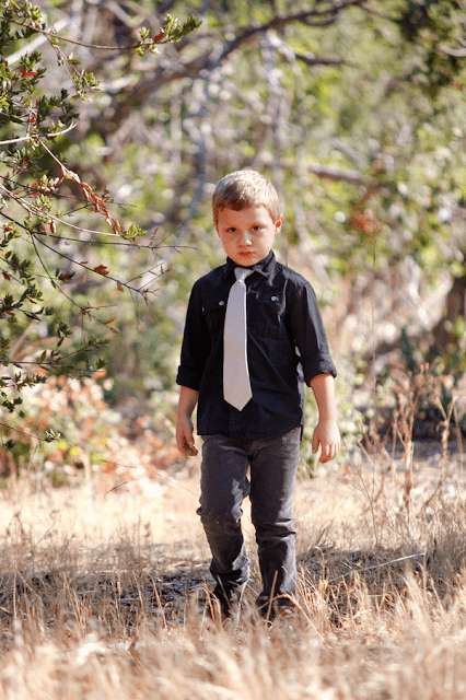 A young boy standing next to a tree