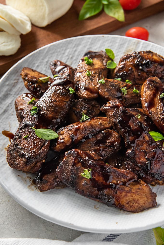 a plate of chicken marinated in balsamic binegar with mozzarella and tomatoes in the background