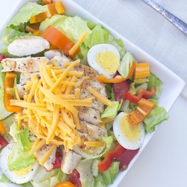 A plate of salad with chicken, cheese, and veggies