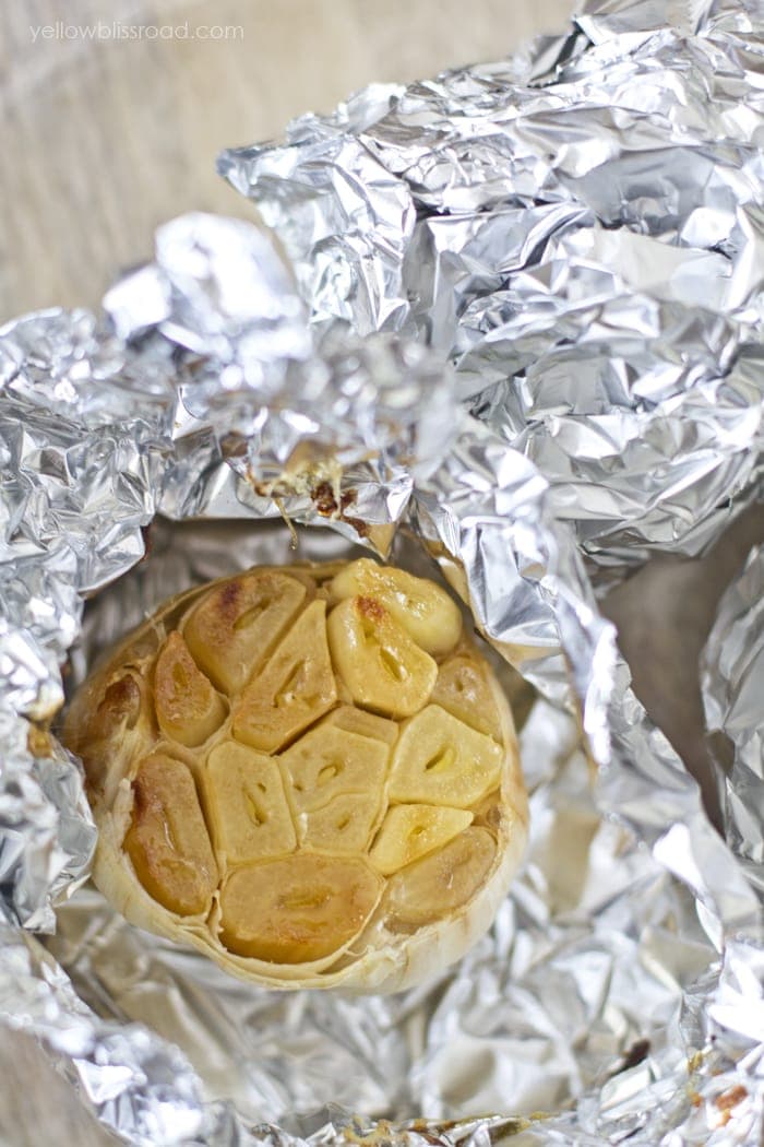 A head of garlic with the top sliced off, roasted in foil.