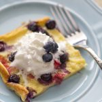 A piece of oven pancake and berries on a plate