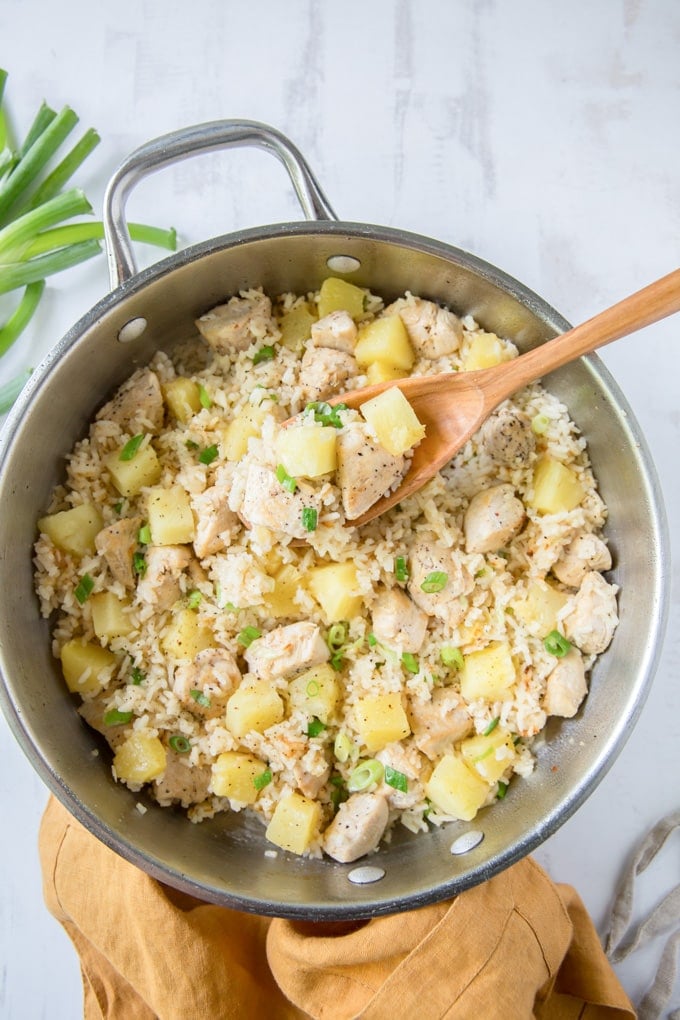 silver pan with rice, chicken and pineapple, with a wooden spoon.