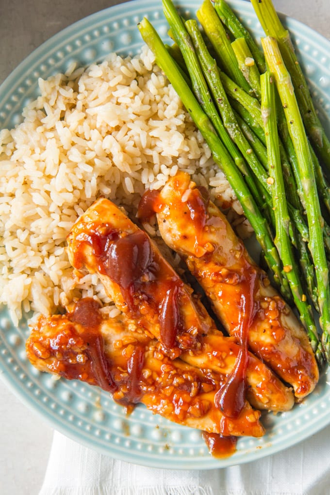 BBQ chicken tenders, rice and asparagus on a plate.