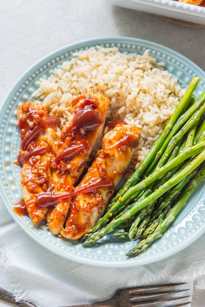 bbq chicken, asparagus and rice on a blue plate.