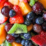 close up of kiwi, strawberries, cantaloupe, grapes with fruit salad dressing.