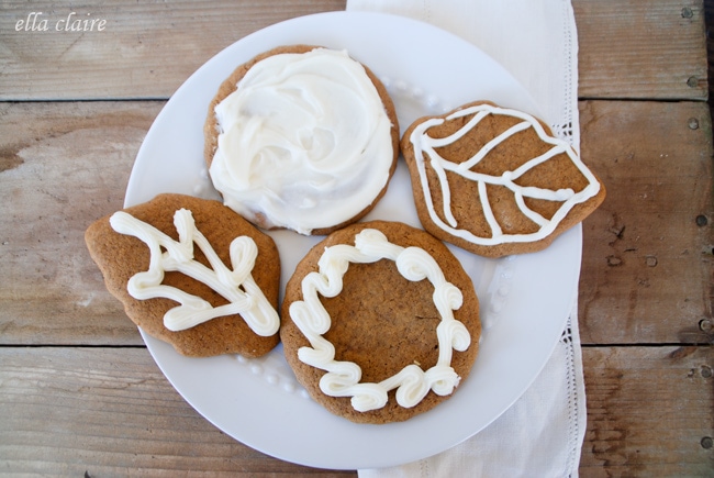 A plate of cookies with frosting sitting on top of a wooden table