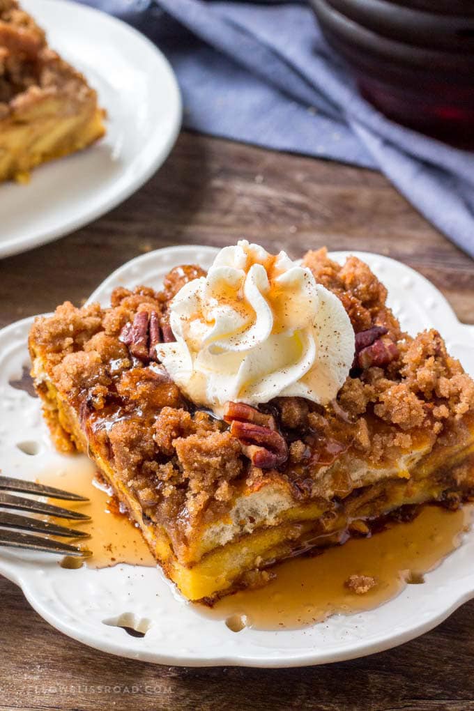 A slice of Pumpkin Pie Baked French Toast with whipped cream and maple syrup.