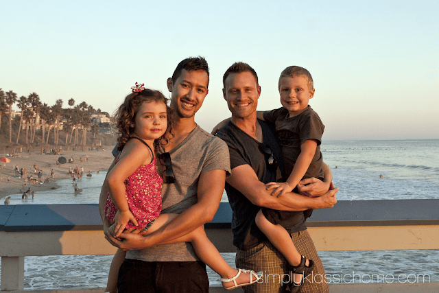 Two men holding two children on the beach