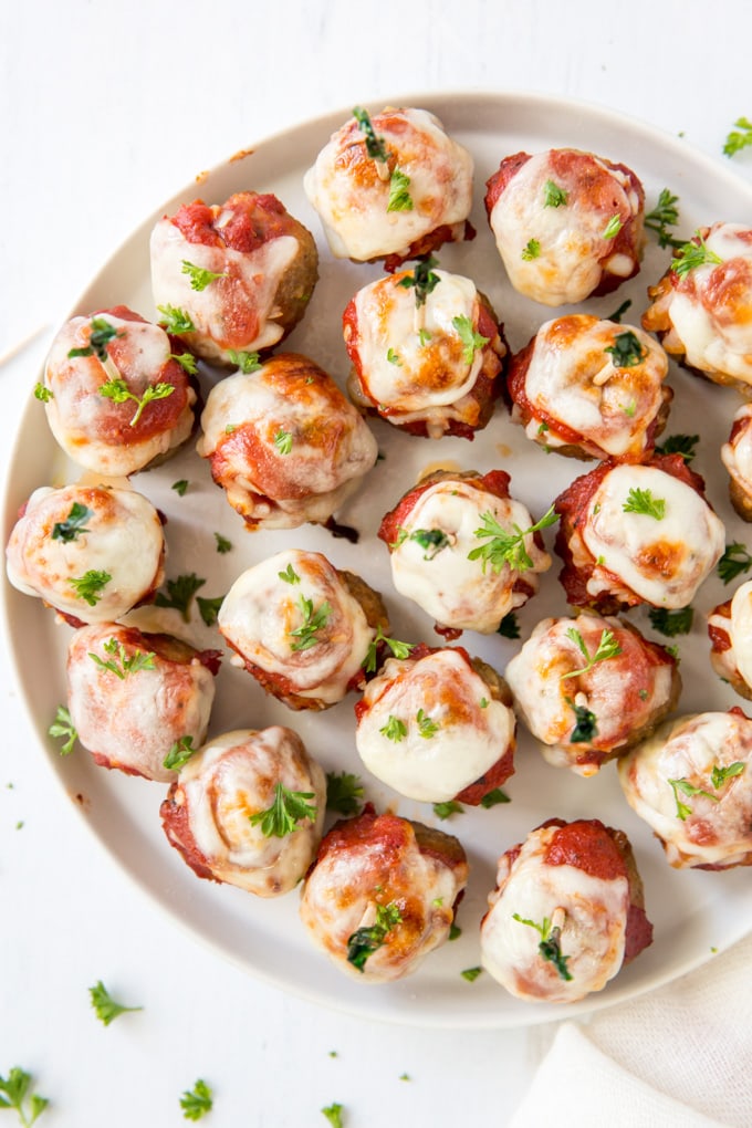 An overhead image of a platter of meatballs with cheese and sauce