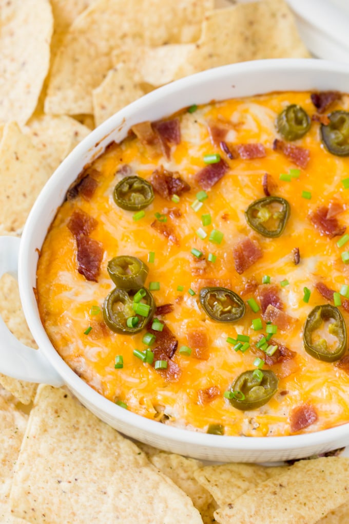 an overhead shot of a cheesy jalapeno corn dip with bacon, surrounded by tortilla chips