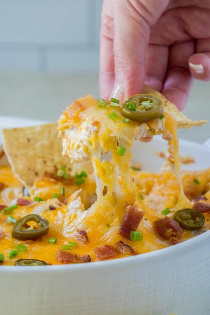 a tortilla being lifted ip out of the jalapeno dip 
