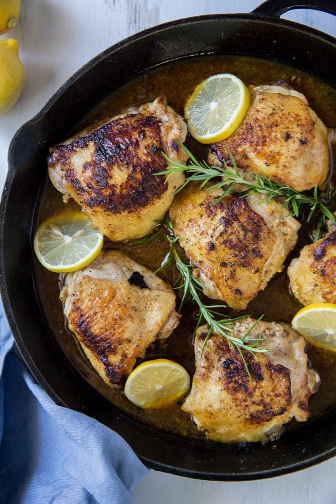 A large skillet with 6 roasted chicken thighs.