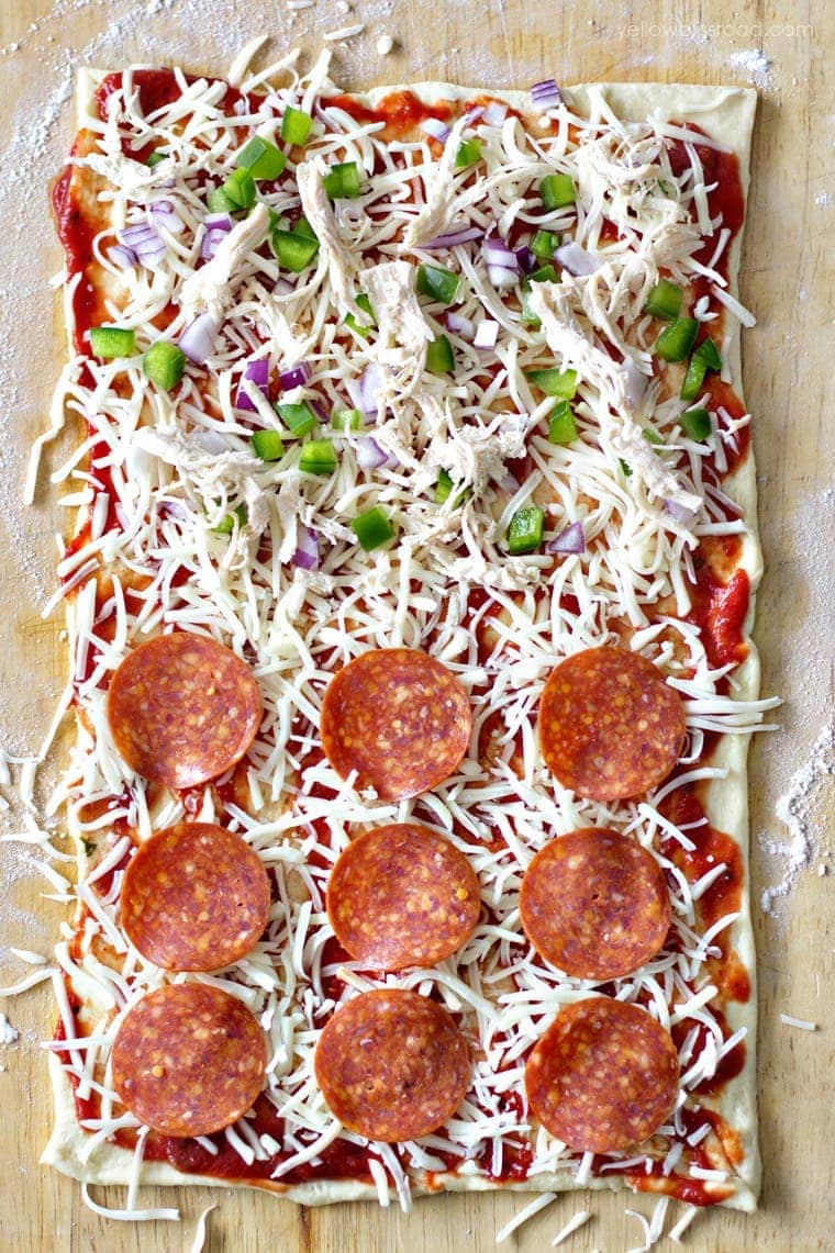 Pizza dough Rolled Out with sauce, pepperoni, cheese and. bell peppers.