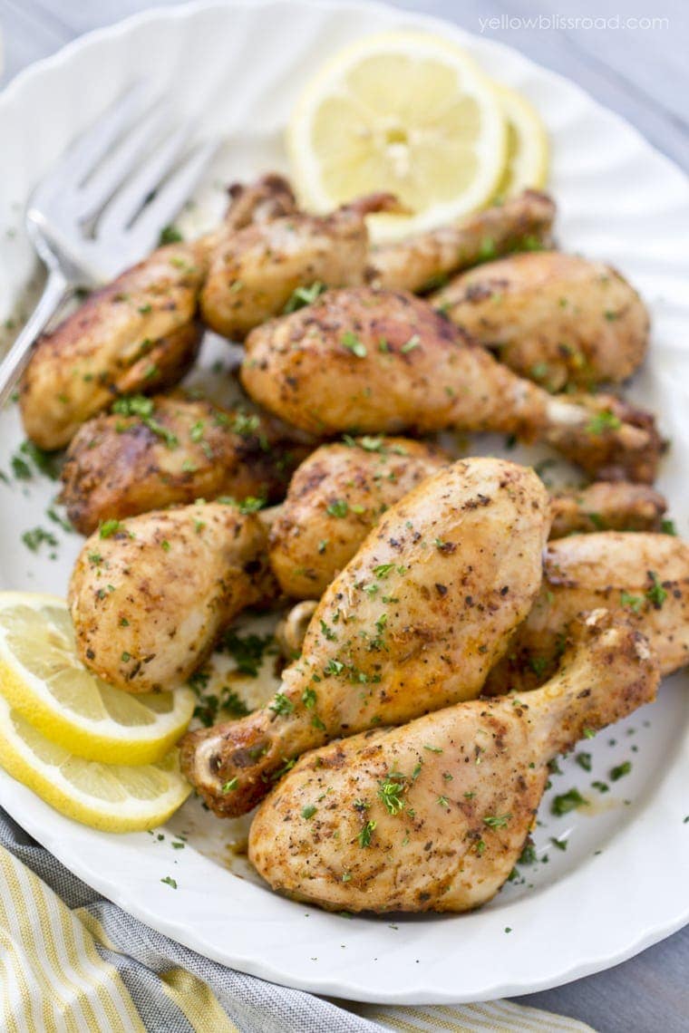 roasted chicken drumsticks on a platter with lemon, parsley and a fork