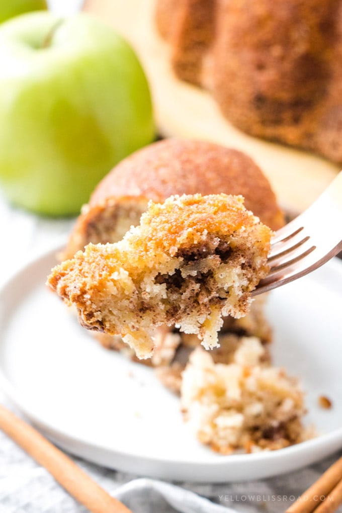 Cinnamon Apple Bundt Cake - With sweet cinnamon swirls and grated tart apples, this delicious apple cake is a perfect dessert for fall. Cinnamon Apple Bundt Cake sliced, with a bit ready on a fork.