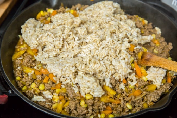 a skillet with ground beef, corn, peppers and rice