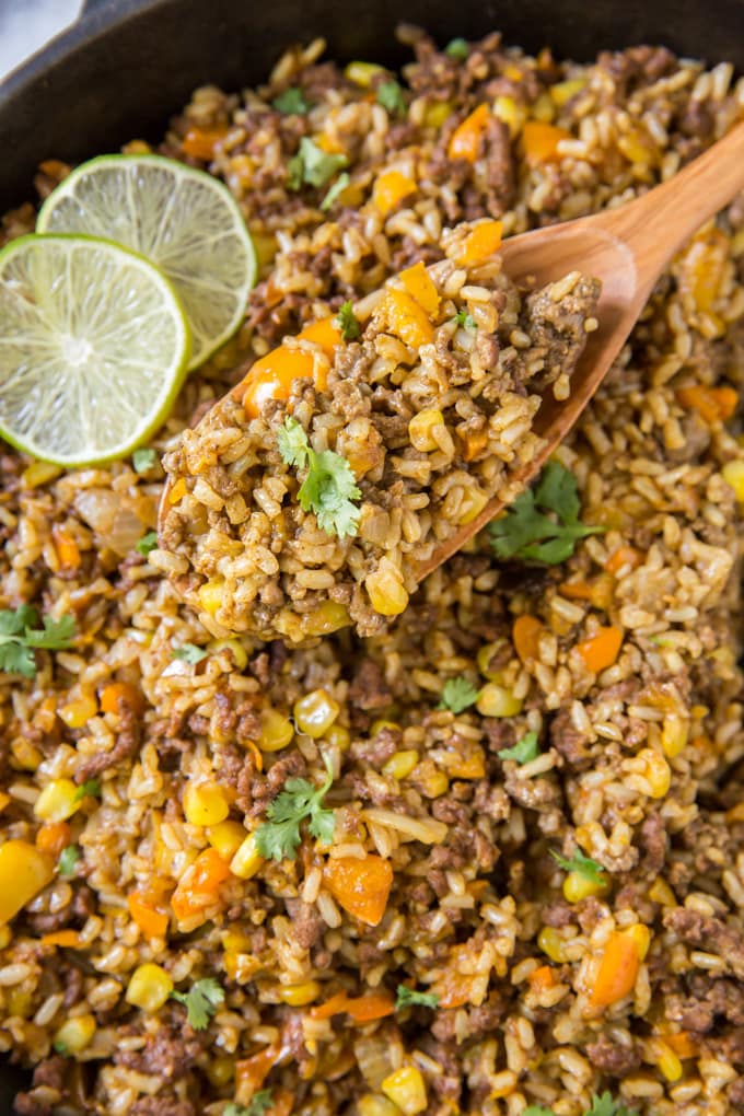 a wooden spoon holding up a serving of ground beef and rice