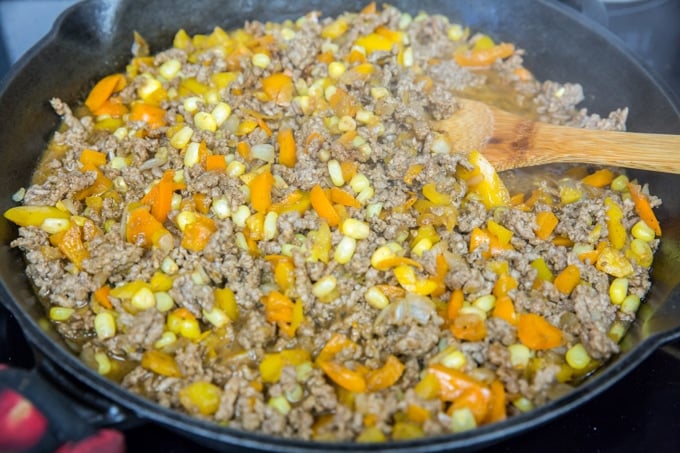 a skillet with ground beef, corn and bell peppers