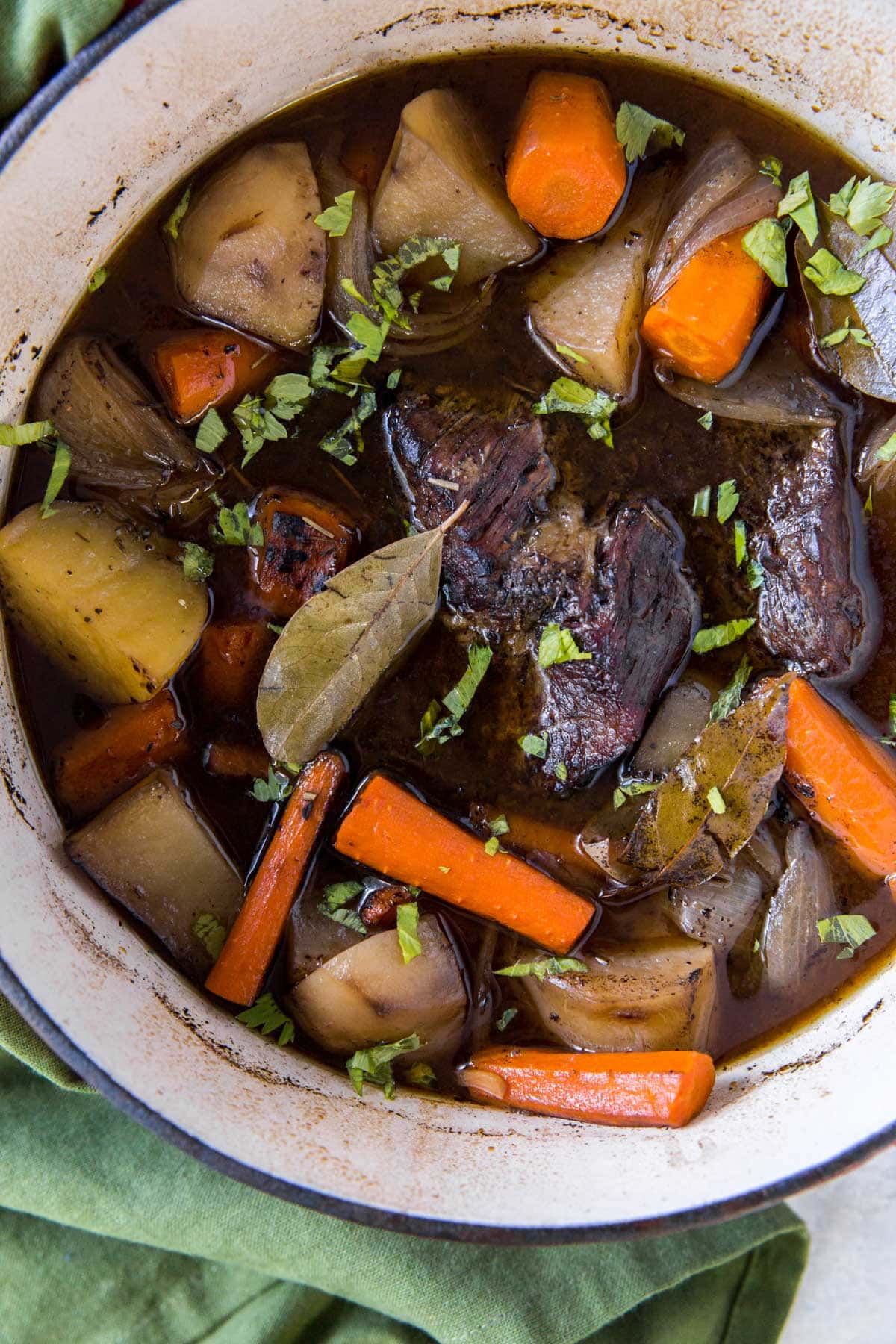 dutch oven with beef broth, carrots, potatoes, onions, herbs and chuck roast