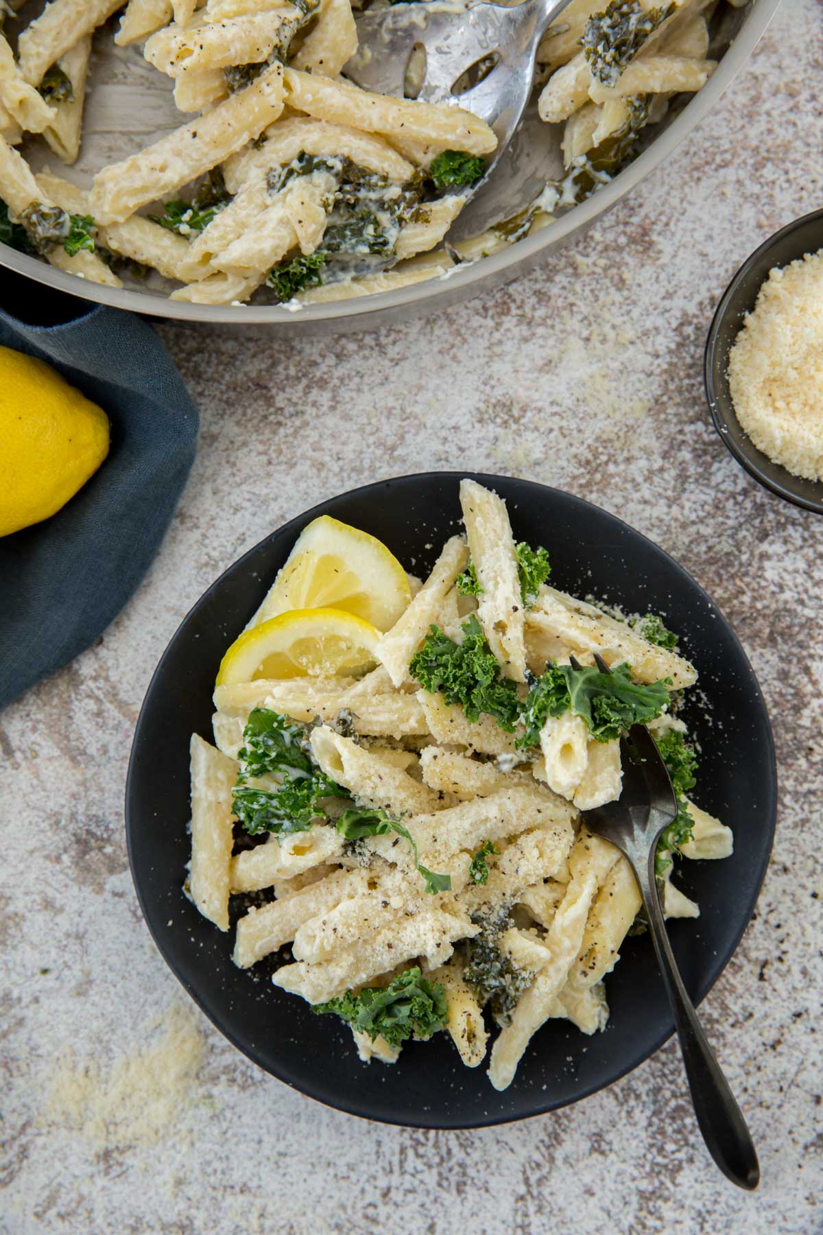 black plate, ricotta lemon pasta, kalem fork, parmesan cheese