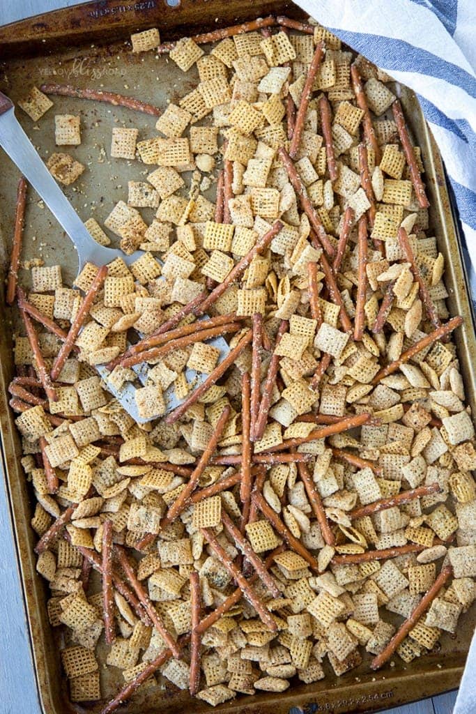 chex mix on a baking sheet with a spatula