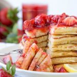 A plate of pancakes with strawberries on top