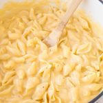 A bowl of shell pasta with cheese sauce.