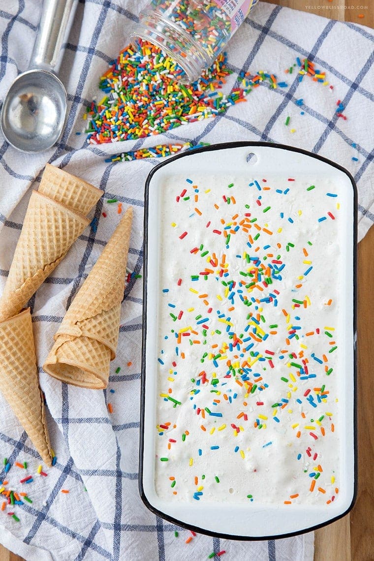 a loaf pan with no churn ice cream and sprinkles, an ice cream scoop, ice cream cones and an ice cream scoop
