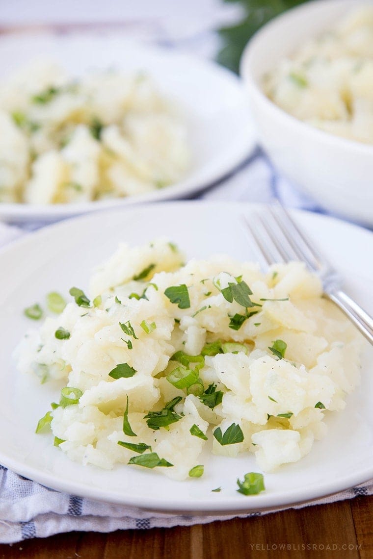Authentic German Potato Salad is a cold salad made with an oil & vinegar dressing that is traditionally served in the Swabian region of Southern Germany. A white plate with german potato salad on it and a fork.