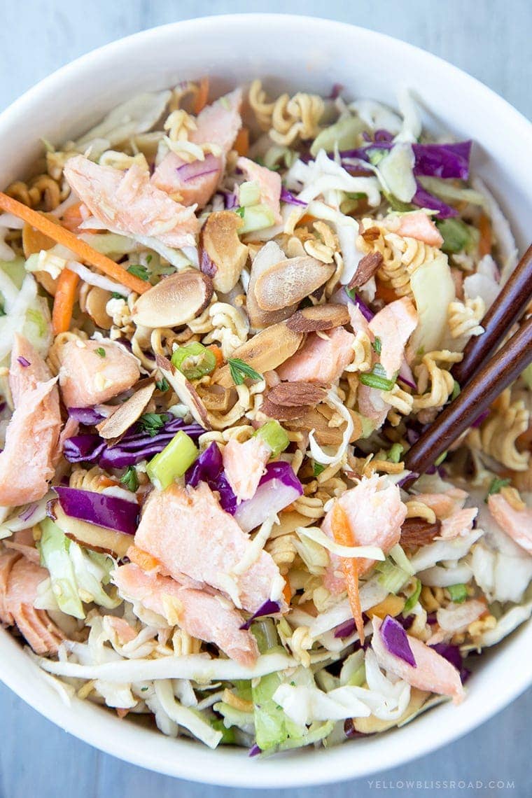 A colse up of a bowl or coleslaw mix with salmon the ramon noodles