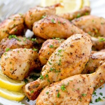 baked chicken drumsticks, white platter, parsley, lemon slices