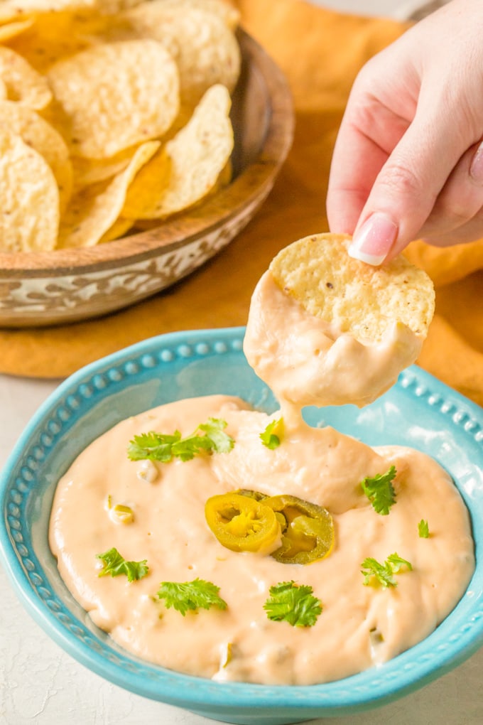 A chip being dipped into a bowl of nacho cheese sauce