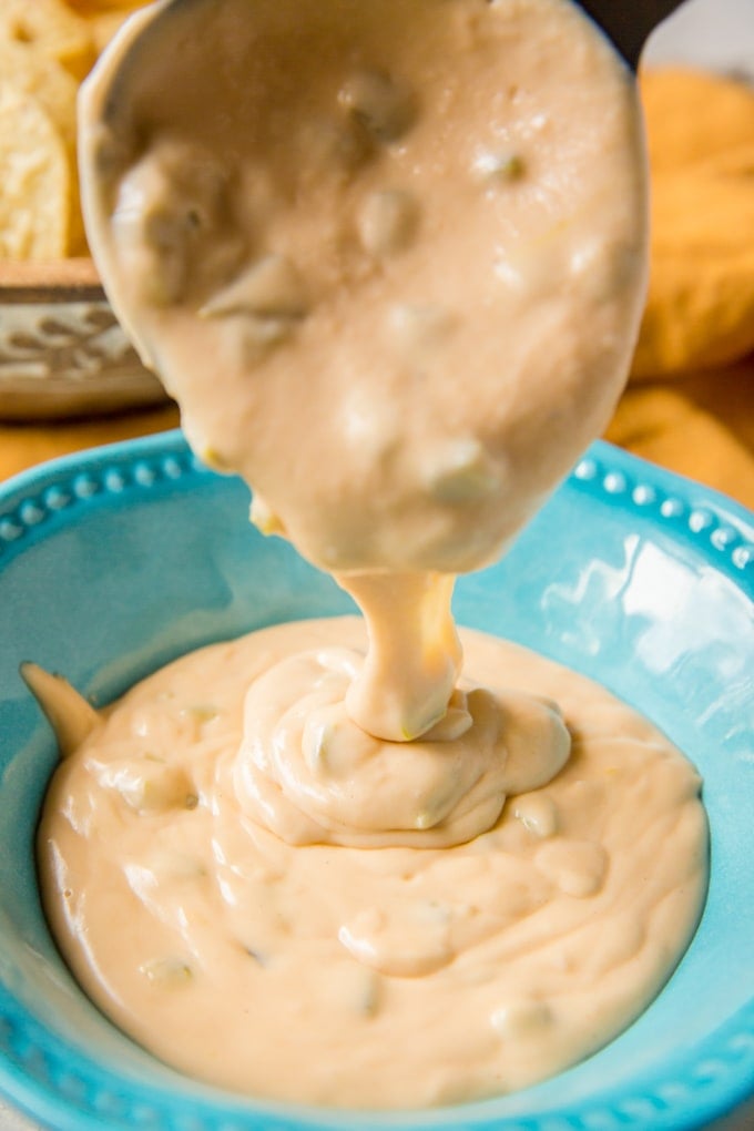 Nacho cheese sauce being poured into a blue bowl.